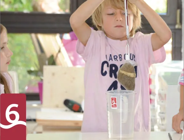 Ein Junge wiegt einen Stein über einem Wasserglas